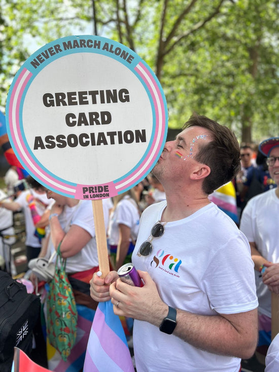 Mark Callaby kissing the Greeting Card Association placard at Pride London 2023