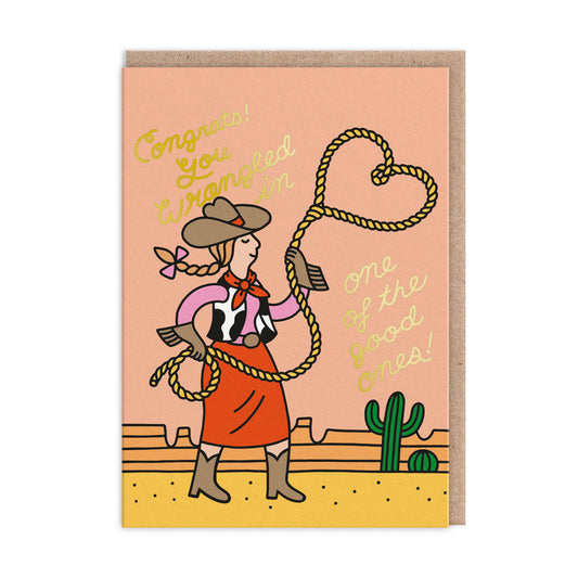 Engagement card with a lassoing cowgirl illustration and gold foil tect that reads "Congrats! You wrangled in one of the good ones!"
